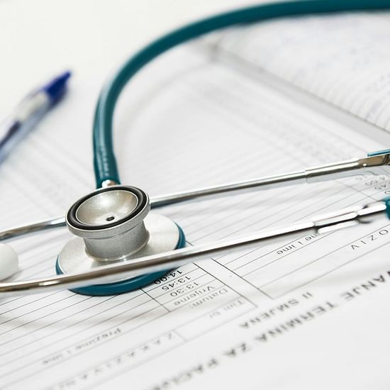 A teal stethoscope and a blue pen rest on top of a patient's medical chart.