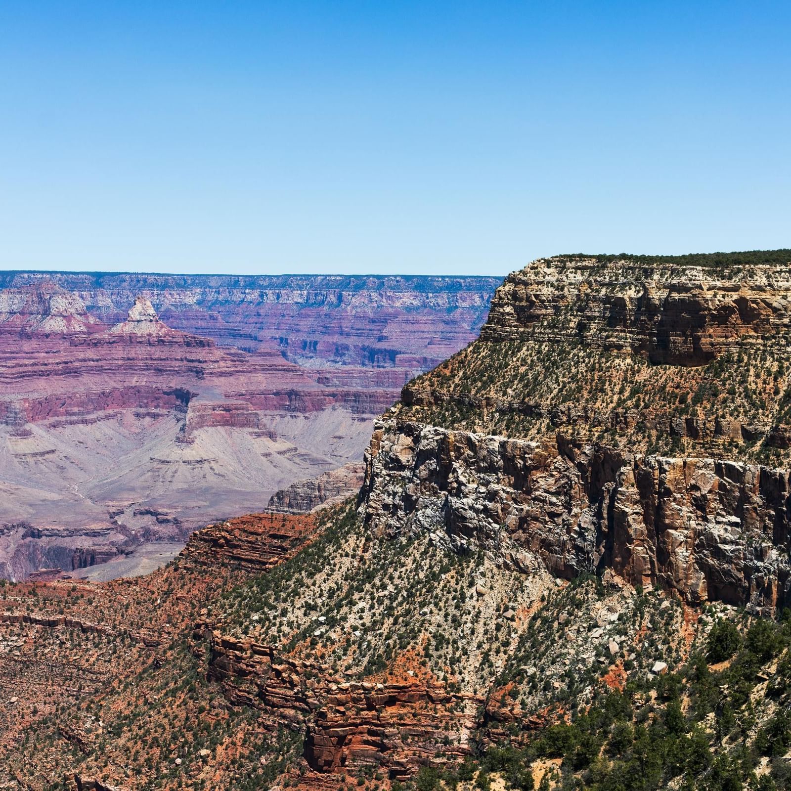 A vast canyon with steep cliffs and rugged terrain, displaying deep valleys and layered rock formations.