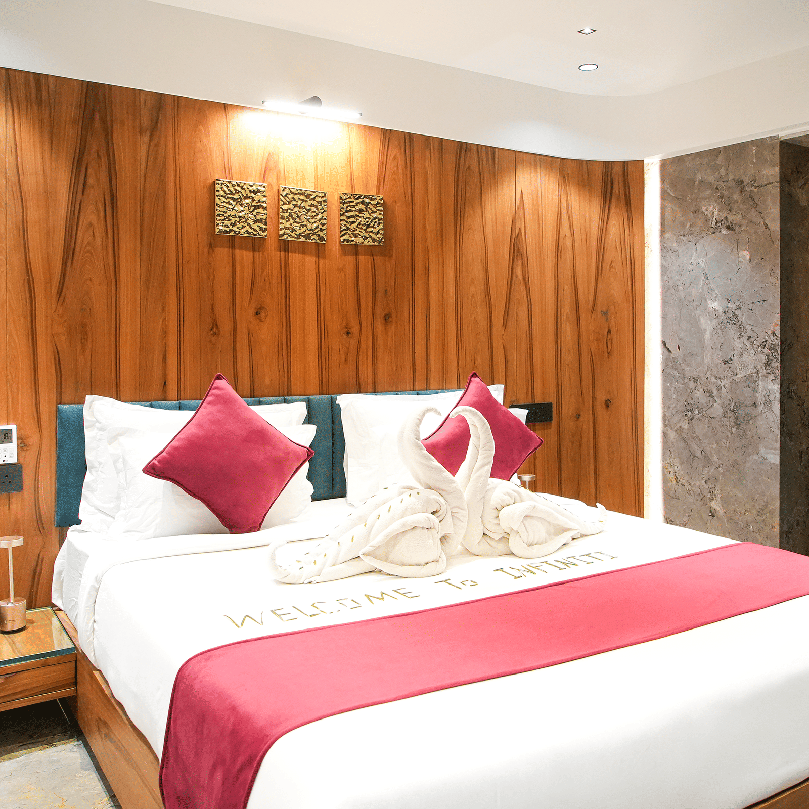 Wooden-panelled bedroom with king bed, red cushions, and dark curtains at Infiniti Hotel, Indore.