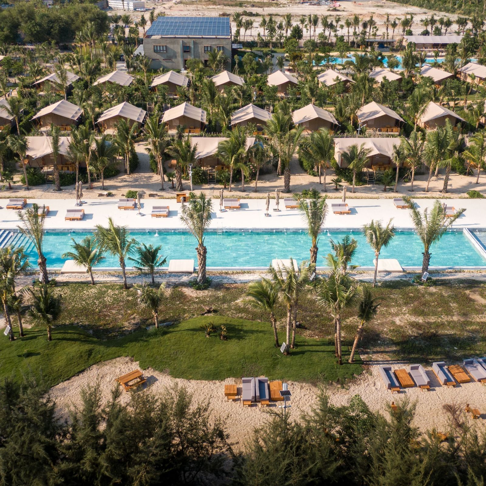 An aerial view of the pool area and surrounding greenery at WoCAL Retreat Ke Ga, showing the Mindful Tent village layout.