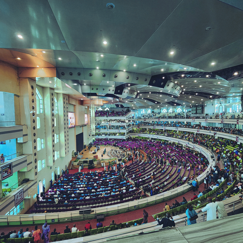 A view from the top of a convention centre in a circular seating arrangement with numerous people sitting attending the event.