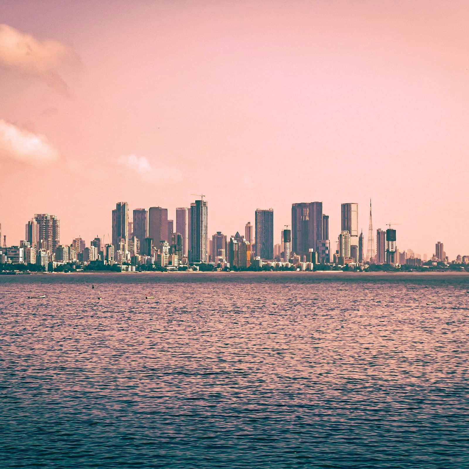  A panoramic view of a city skyline with towering buildings, set against a vast body of water in the background.