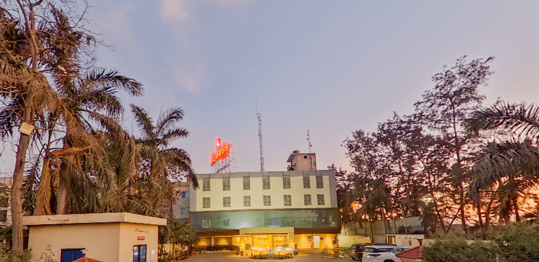 Exterior view of Lords Eco Inn Dahej at sunset showing hotel entrance, landscaped gardens, palm trees, and welcoming facade with signage