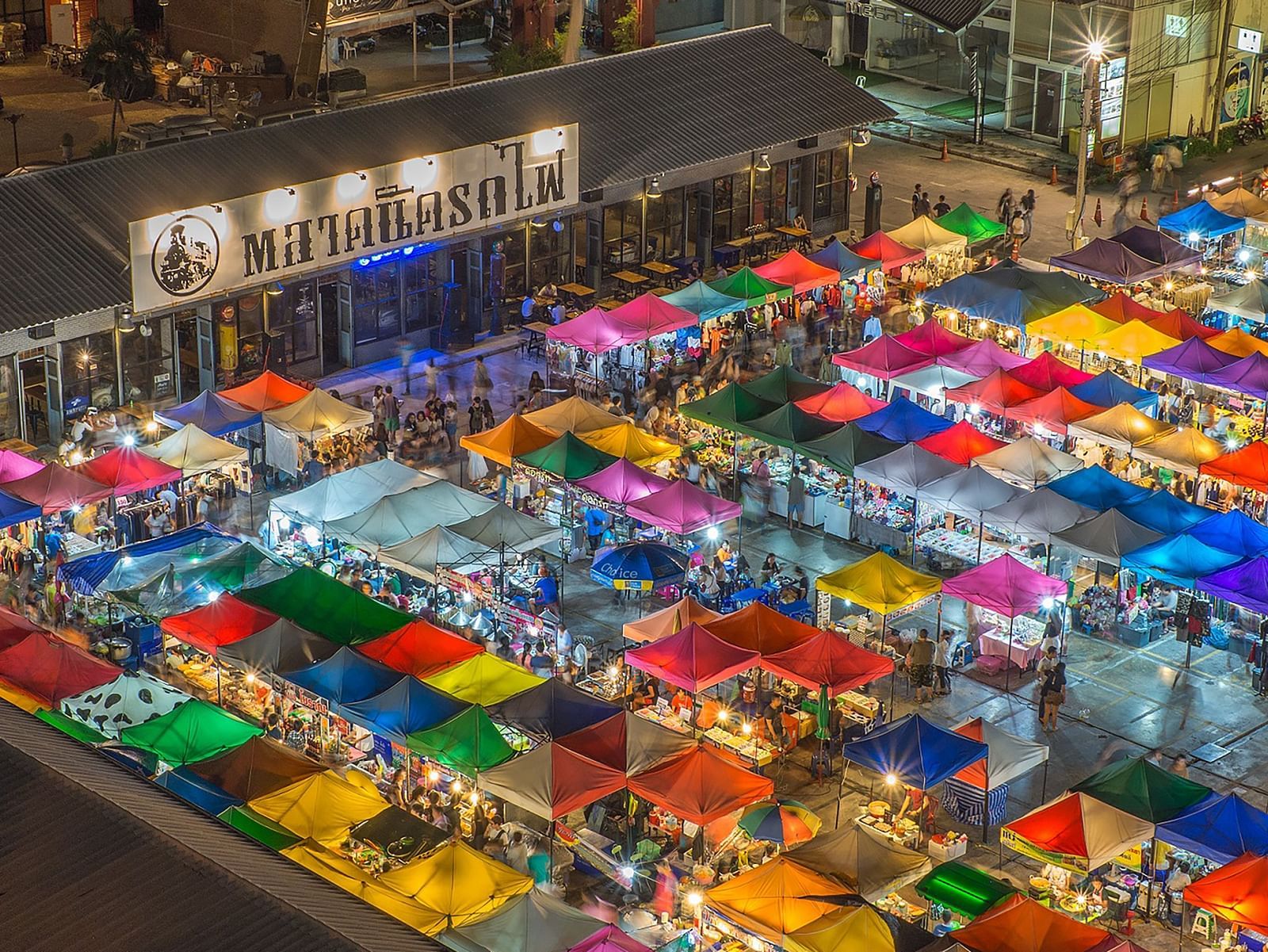 an aerial view of a night market with many shops and people in view.
