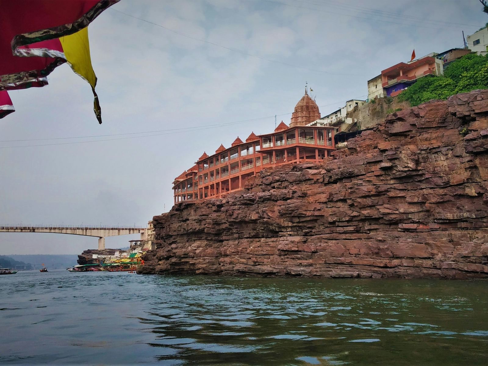 Rocky riverside cliff with temple structures built on top and the river below.