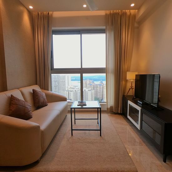 A living room featuring a sofa a coffee table and a TV - Maxxvalue Apartment Powai