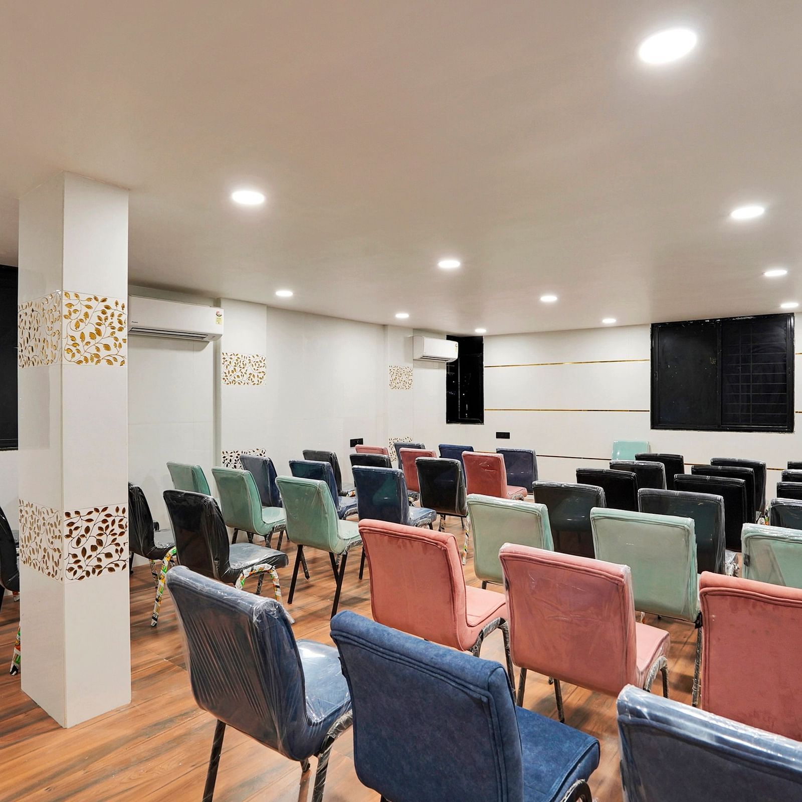 A conference hall with chairs facing the screen at Hotel Regal Heaven, Pune.