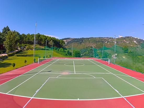 Multi-sport court with basketball hoops and tennis lines set against stunning mountain backdrop at The Manor Wellness & Sports Hotel