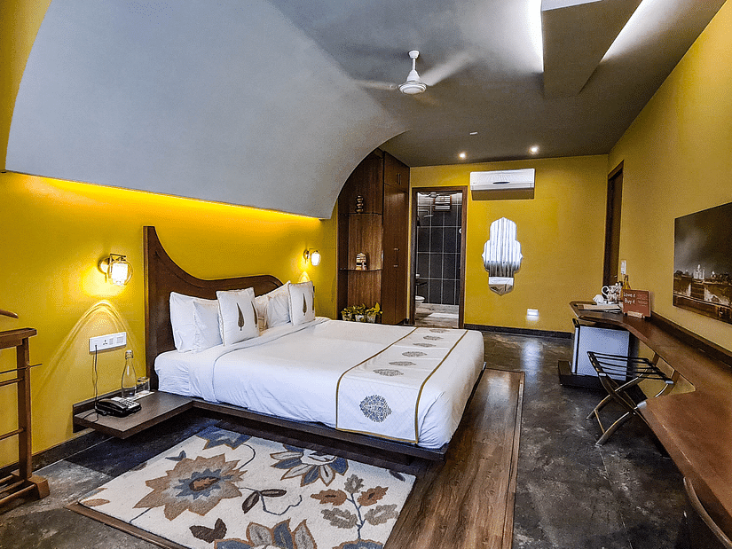 A bedroom with a double bed, side stand and a work desk and chair
