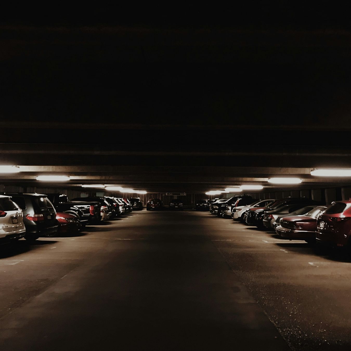 Dimly lit underground parking lot with rows of parked cars