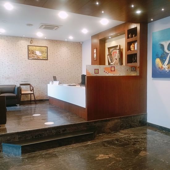A reception area featuring a booking counter a waiting space with sofas and a table - Mysore Gate Hotel Bangalore