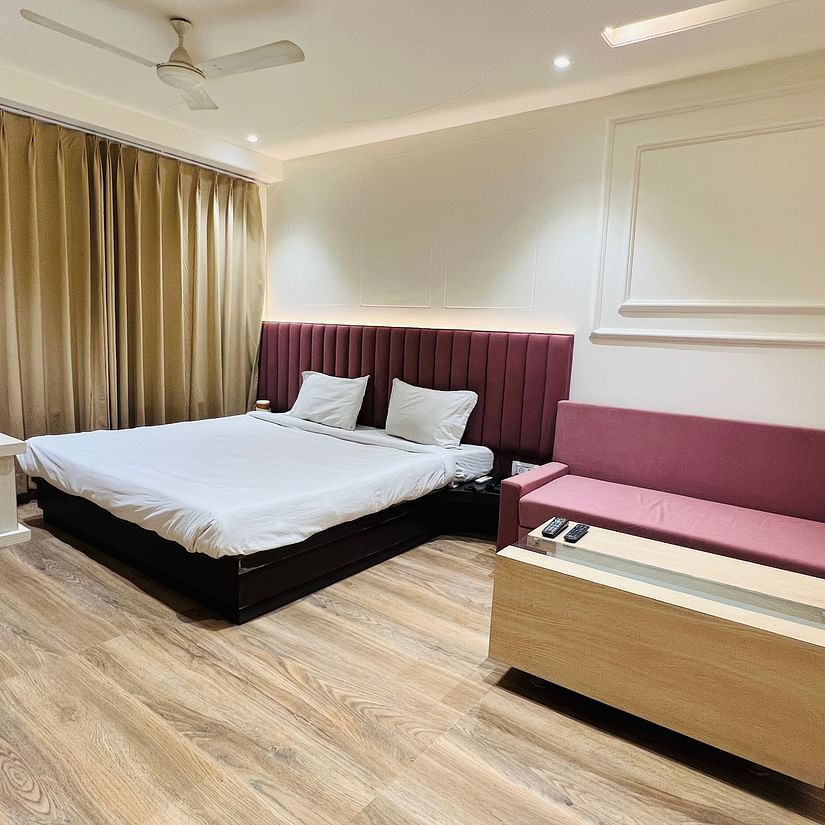 Premium Bedroom with white beddings, mahognagy headrest and mathcing sofa - Hotel Morya, Bhopal