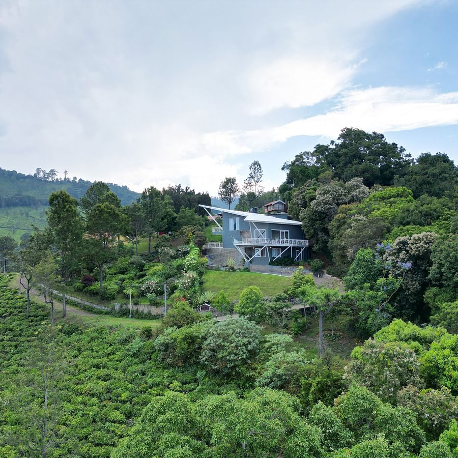 Panoramic view of tree-covered hills with a blue sky in the background at Ibex Resorts, Coonoor (Tapas).
