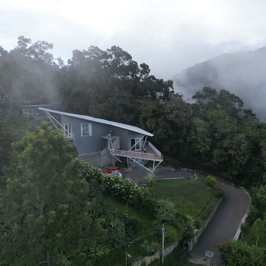 Angled view of a modern house overlooking a scenic coastal landscape with greenery Ibex Resorts, Coonoor (Tapas).