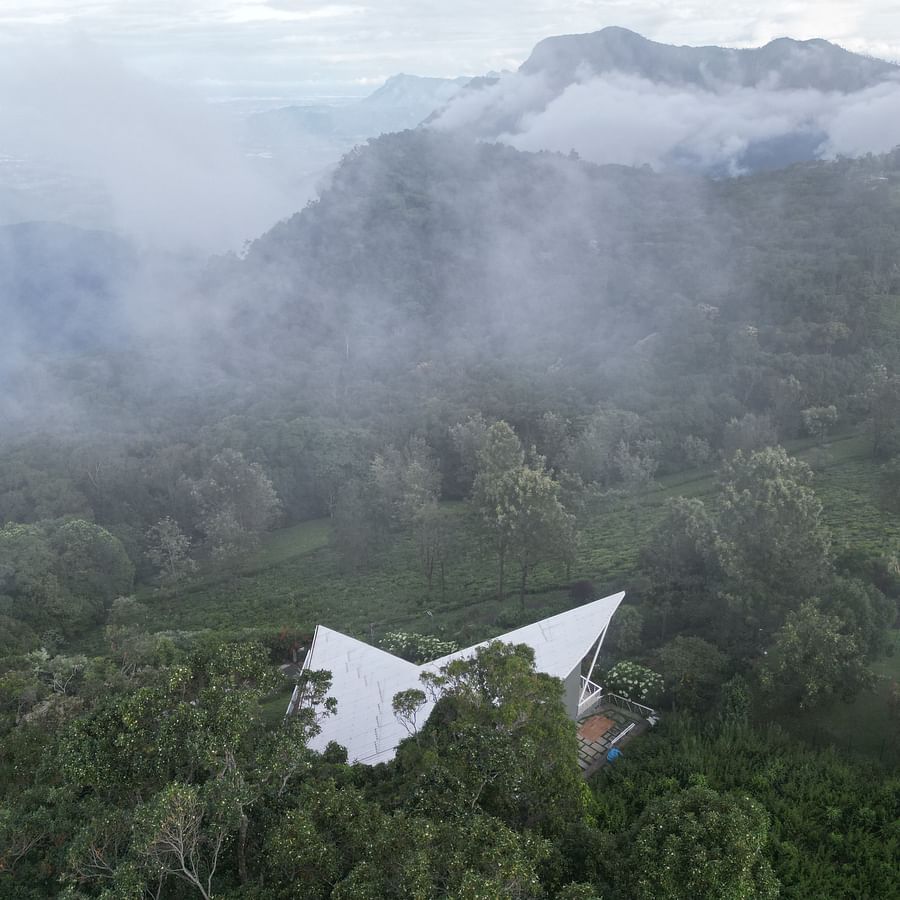 Home on a winding road through misty hills with forest and mountains in the background at Ibex Resorts, Coonoor (Tapas).