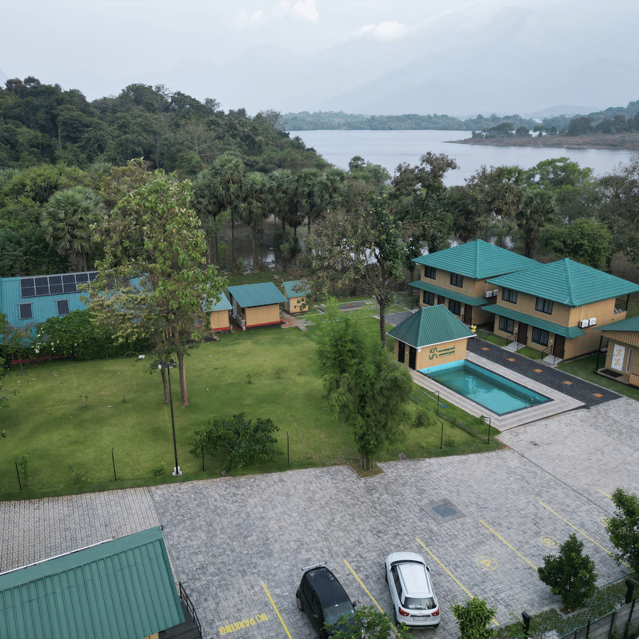 Wide aerial shot showing the resort layout including the swimming pool, guest cottages, and surrounding forest - Ibex Resorts, Malampuzha (Kava Eco Camp and Caravan Park)