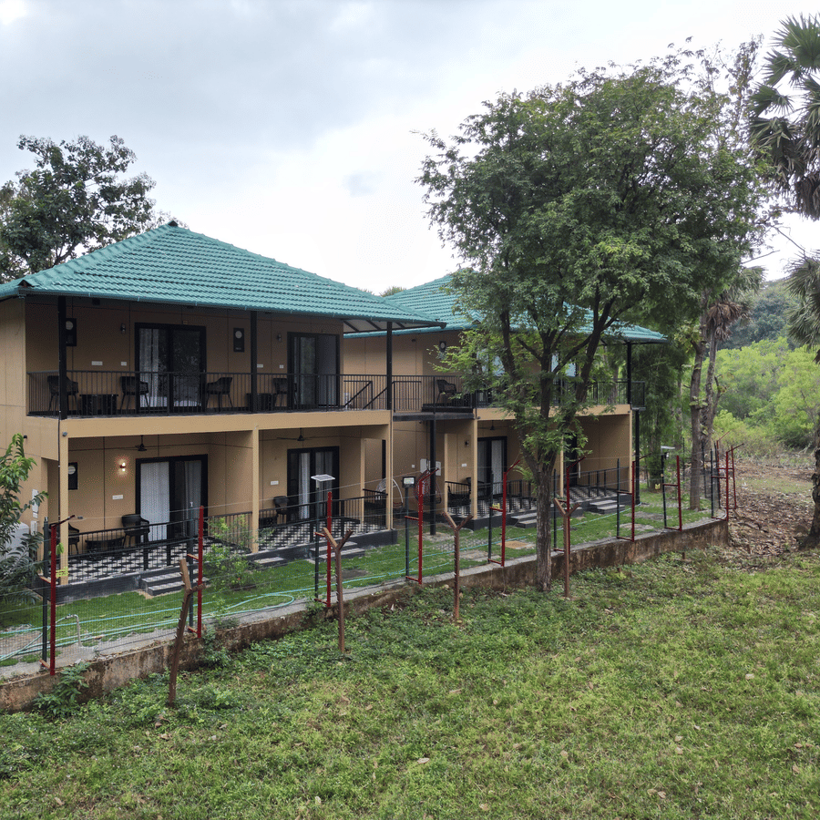 2-storey resort building with private balconies surrounded by a lush natural landscape and tall trees - Ibex Resorts, Malampuzha (Kava Eco Camp and Caravan Park)