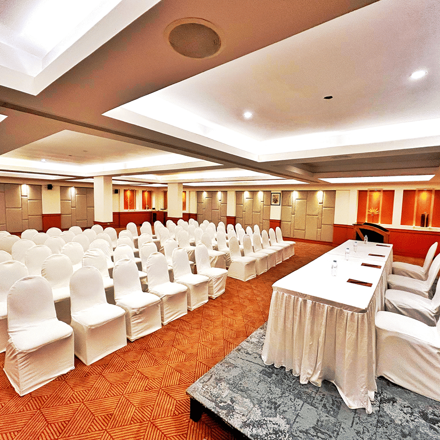 Banquet hall set up in theatre-style seating with white chairs and a head table at The Residency Karur, ideal for conferences and formal gatherings