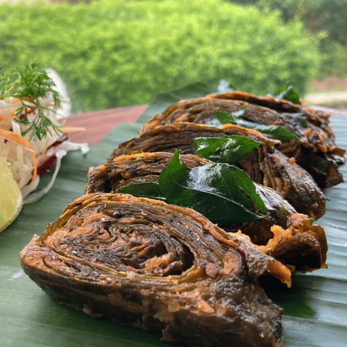 A bunch of pathrode are arranged on a banana leaf with colourful chutneys