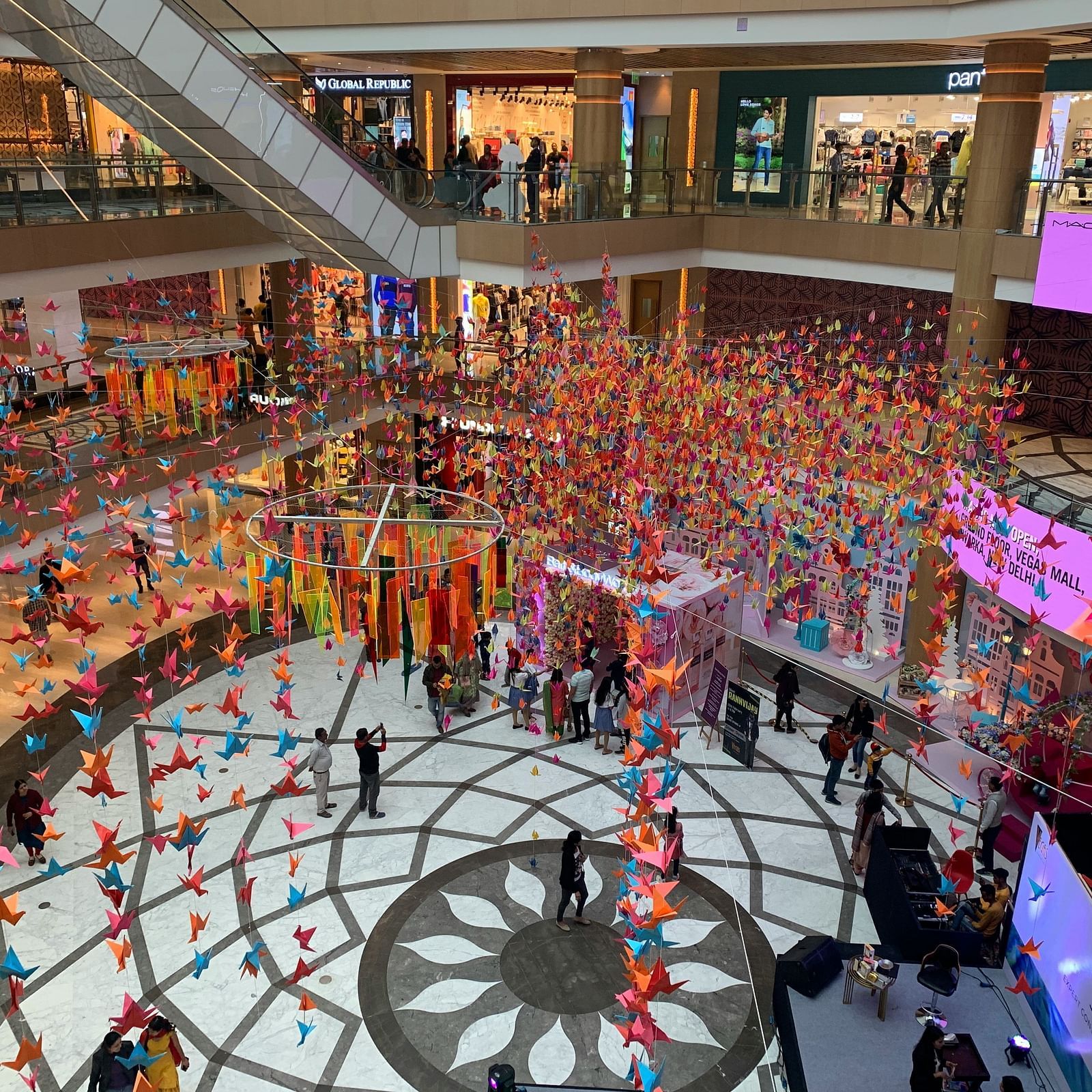 A vibrant indoor shopping mall filled with colourful decorations and crowds, creating a festive atmosphere