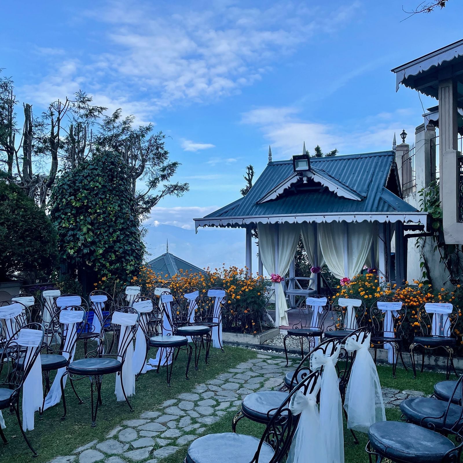 Outdoor seating setup at Cedar Inn, Darjeeling, arranged on the lawn with scenic views and a stage area for events or celebrations.