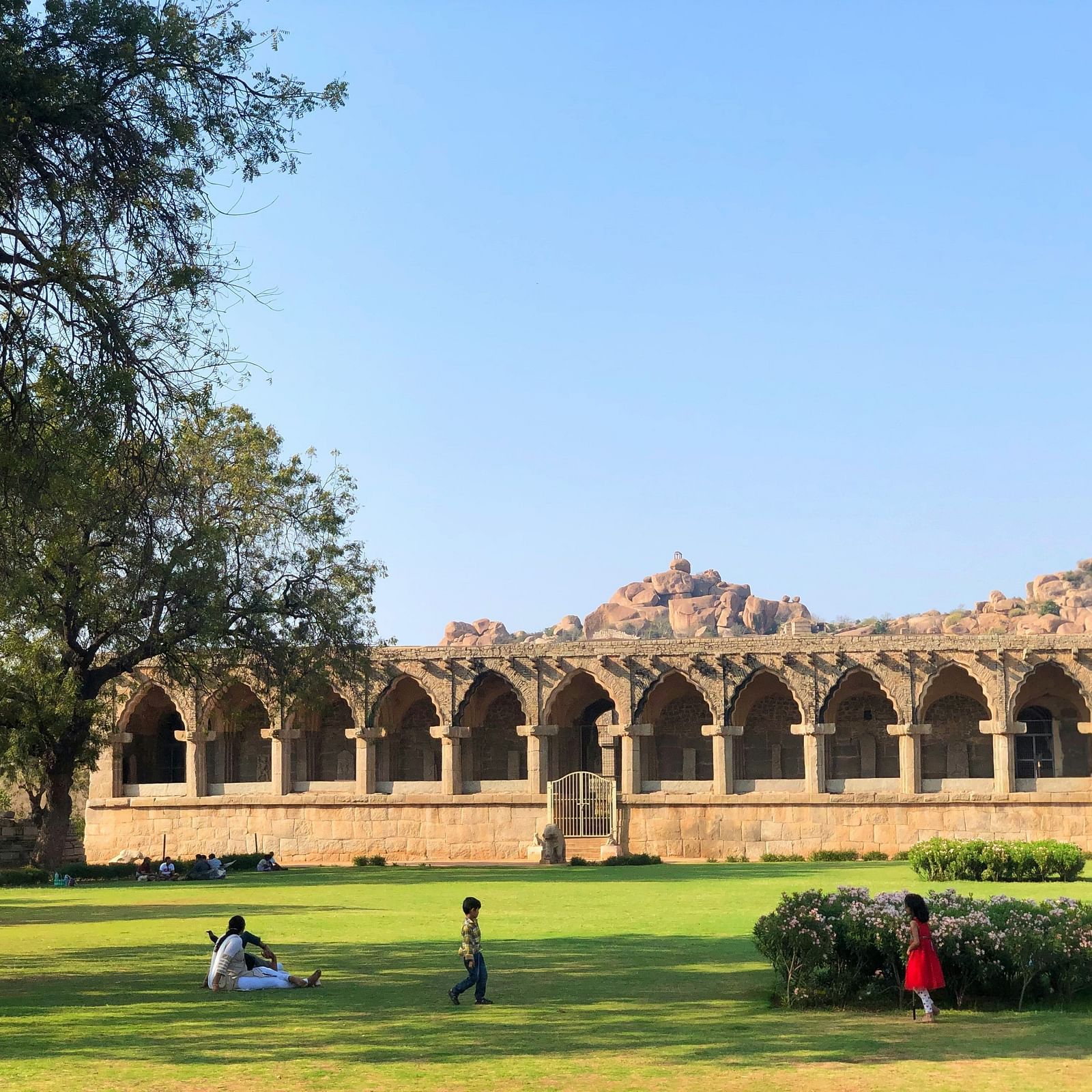 A public park in front of a one storeyed monument where people are relaxing | Diamond Parks, Pune