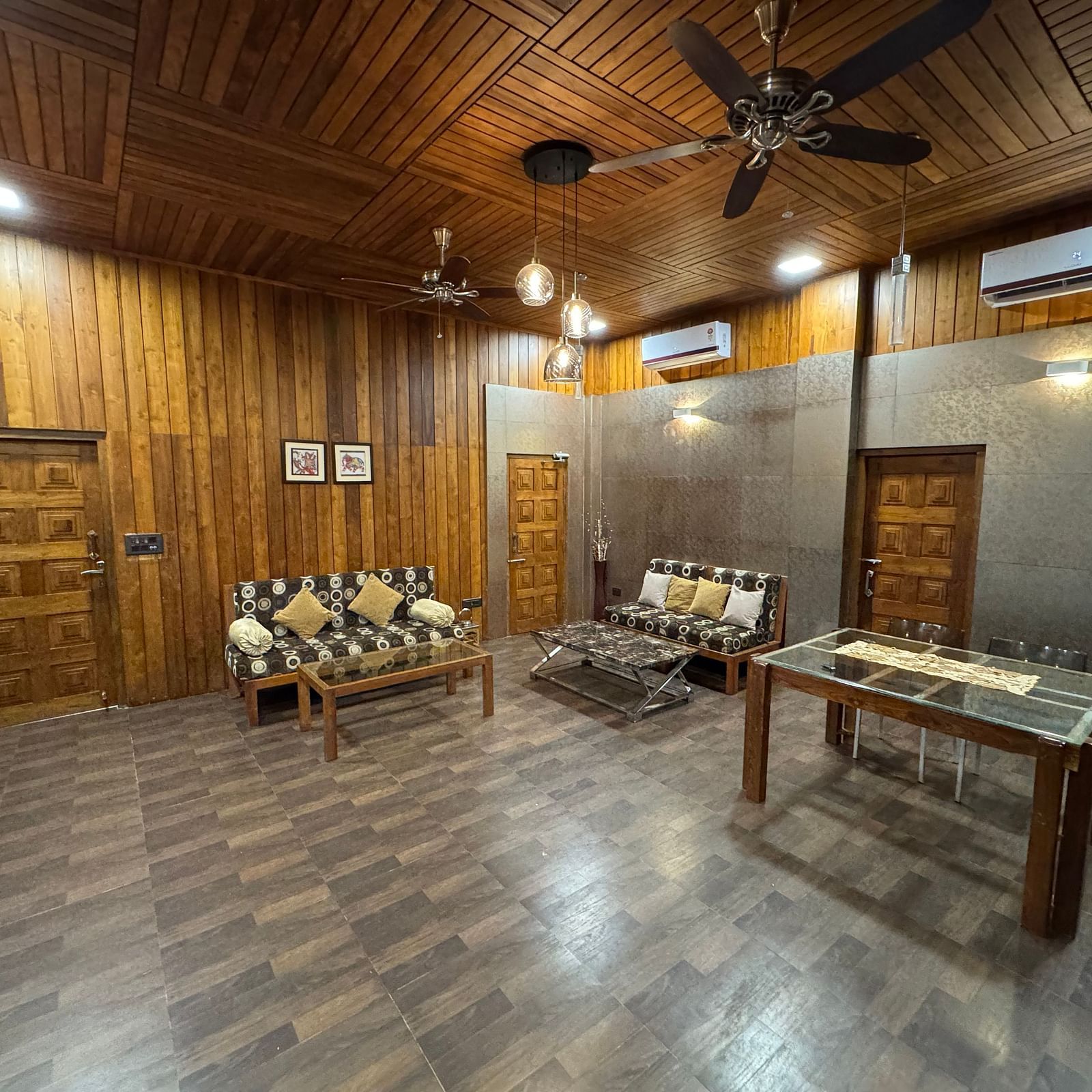 A wide-angle view of a rustic living area with wooden walls and ceiling, a patterned sofa, and a wooden coffee table.