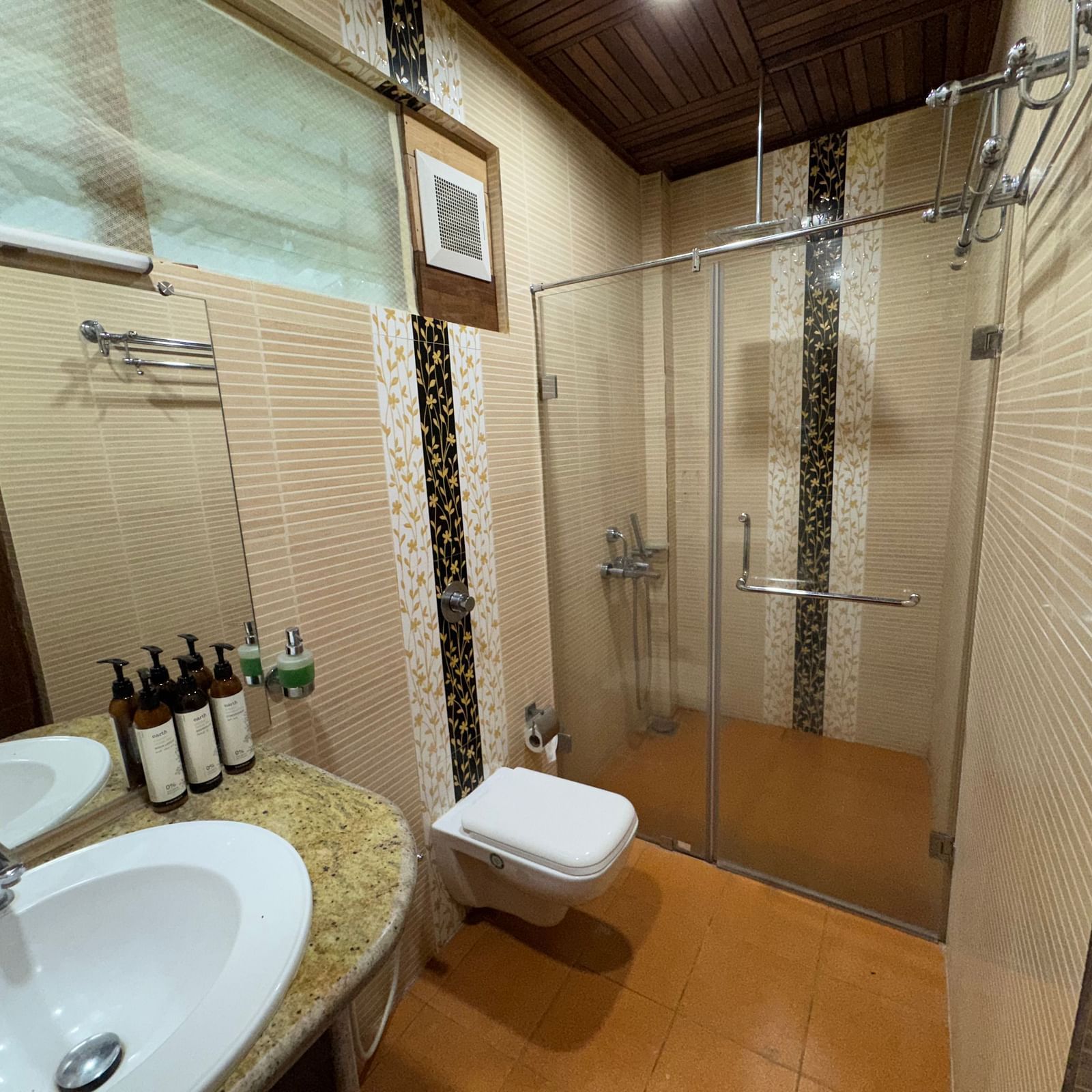 A bathroom with a double vanity, a large mirror, and a glass-enclosed shower area, showcasing toiletries on the counter.