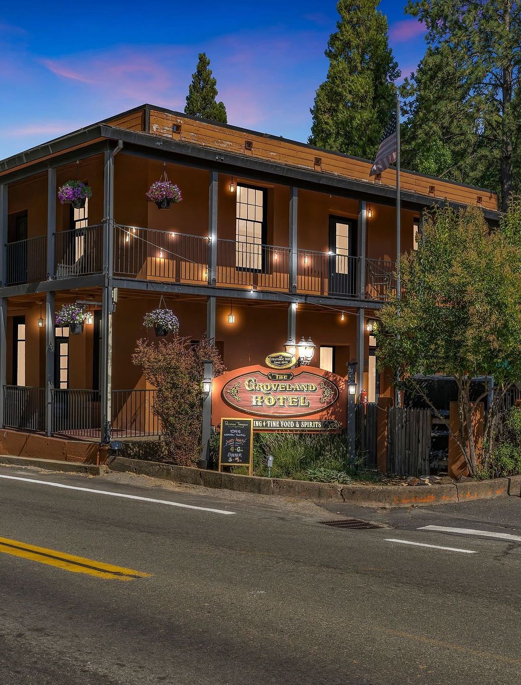 Facade of The Groveland Hotel surrounded by trees during blue hour