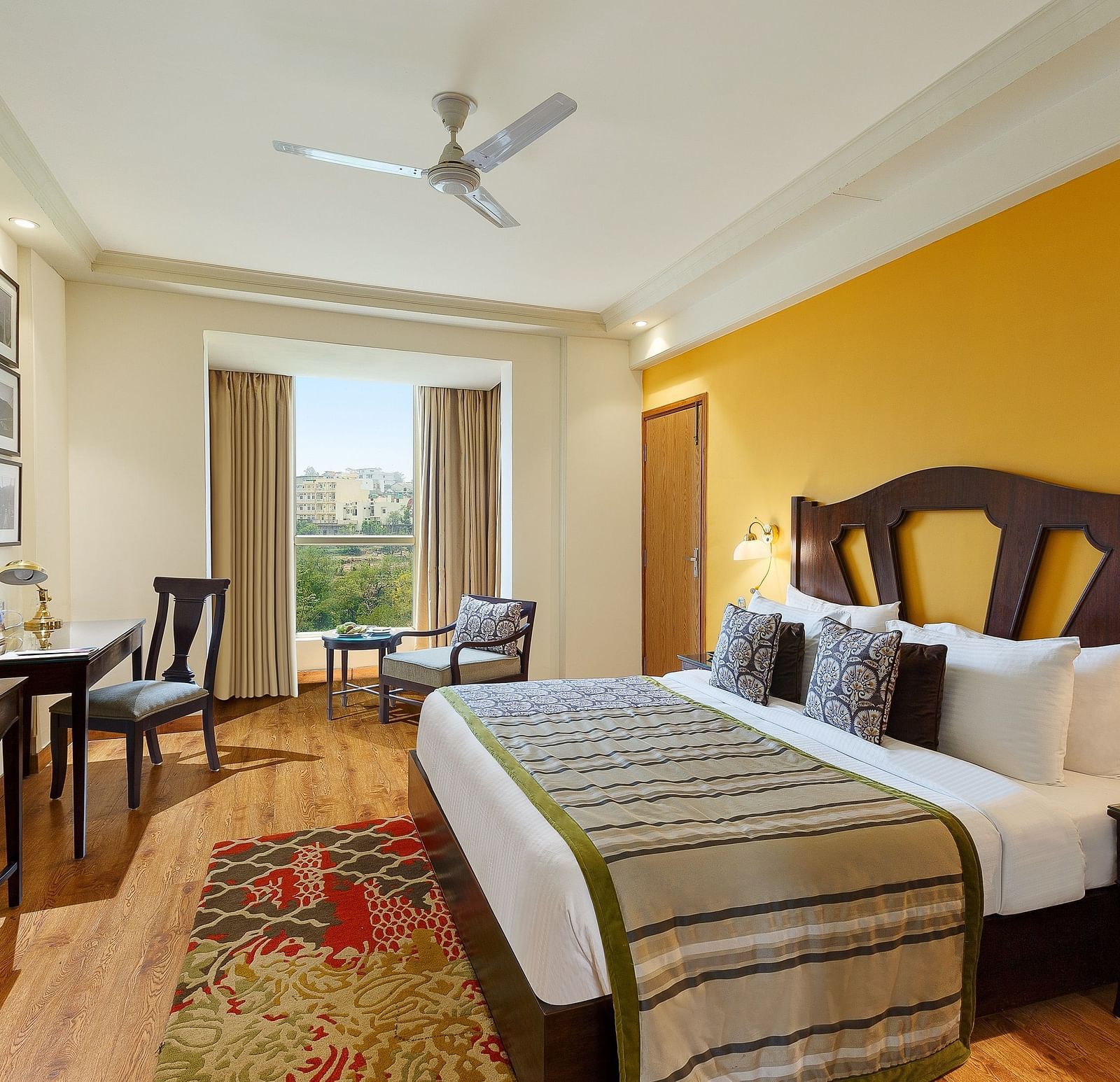 An image of the room features a king-size bed with a plush headboard and comfortable bedding. A comfortable armchair sits by the window, offering a view of the outdoors. 
