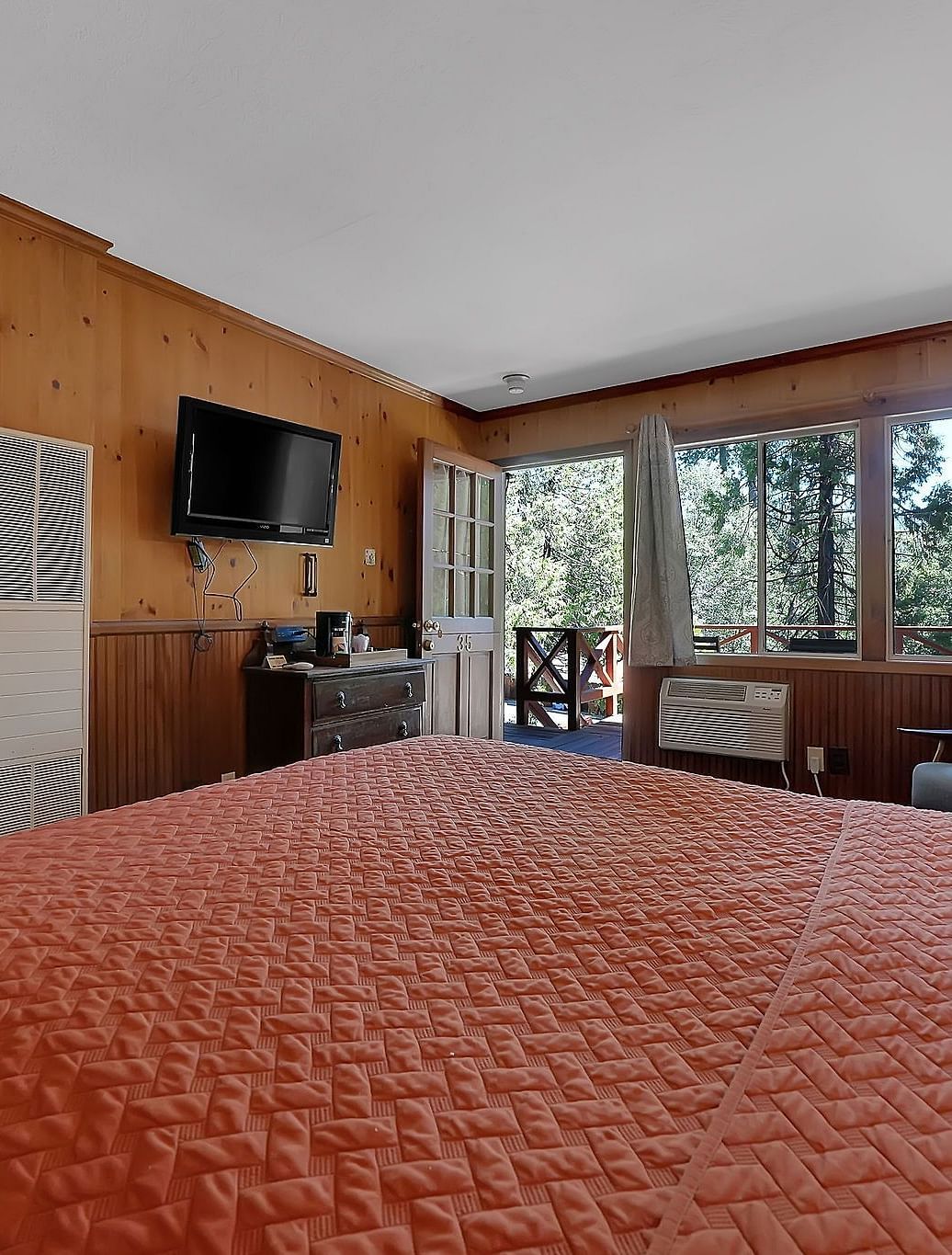 A double bed in a room with a television and large windows