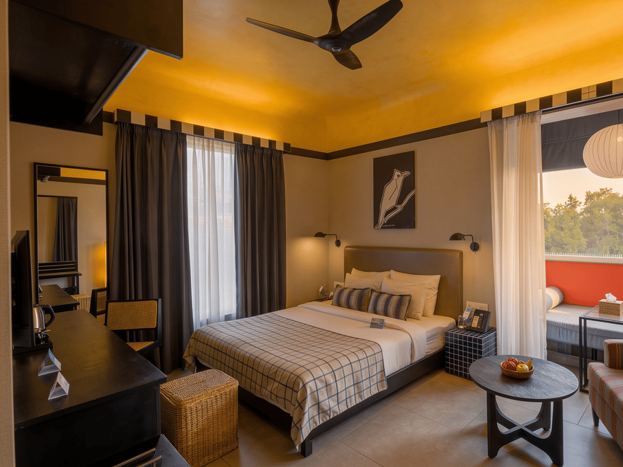A hotel room containing a king size bed, a ceiling fan, a small coffee table, and an armchair next to a balcony at The Sierra - By The Lake.