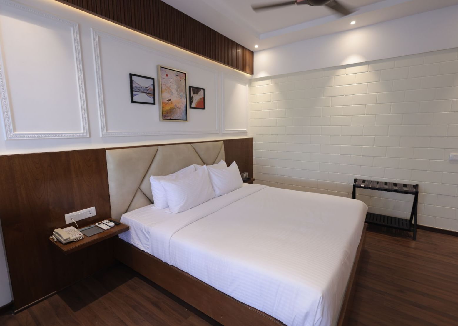 A room with double bed, bedside table and framed art work at Trishvam Symphony, Krishnagiri