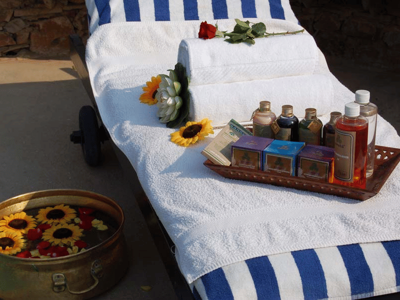 A stripped towel spread across a spa bed at Neemrana's Glasshouse on The Ganges, Rishikesh, featuring a tray with essential oils placed on it.