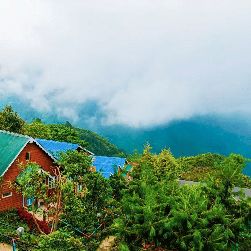 Beautiful resort in Kurseong with colorful cottages, surrounded by lush green hills, pine trees, and misty clouds overlooking the Himalayan valley — perfect stay for nature lovers in Darjeeling