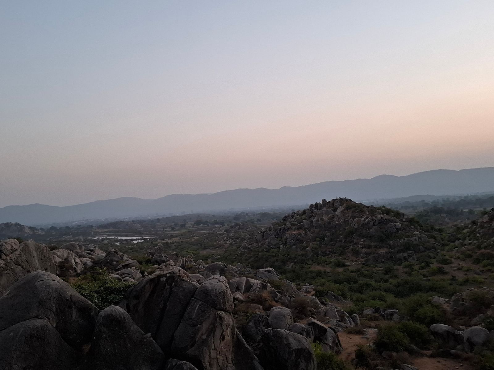 Aerial view of a land with huge rocks and visuals of lake at a far away distance