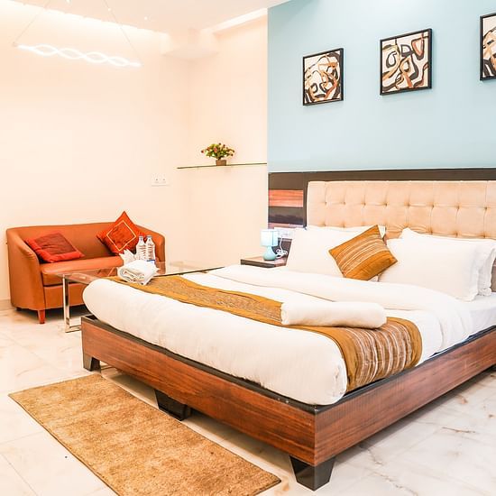 A hotel room featuring a bed, a sofa, and wall decorations - Asian Suites Cyber Park, Gurgaon. 