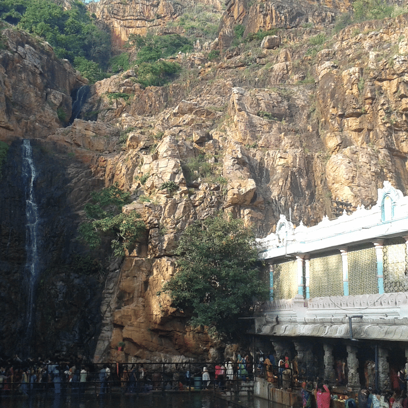 An overview of the Kapila Theertham Temple, carved into the rocky base of the Tirumala Hills, stands beside a sacred waterfall.