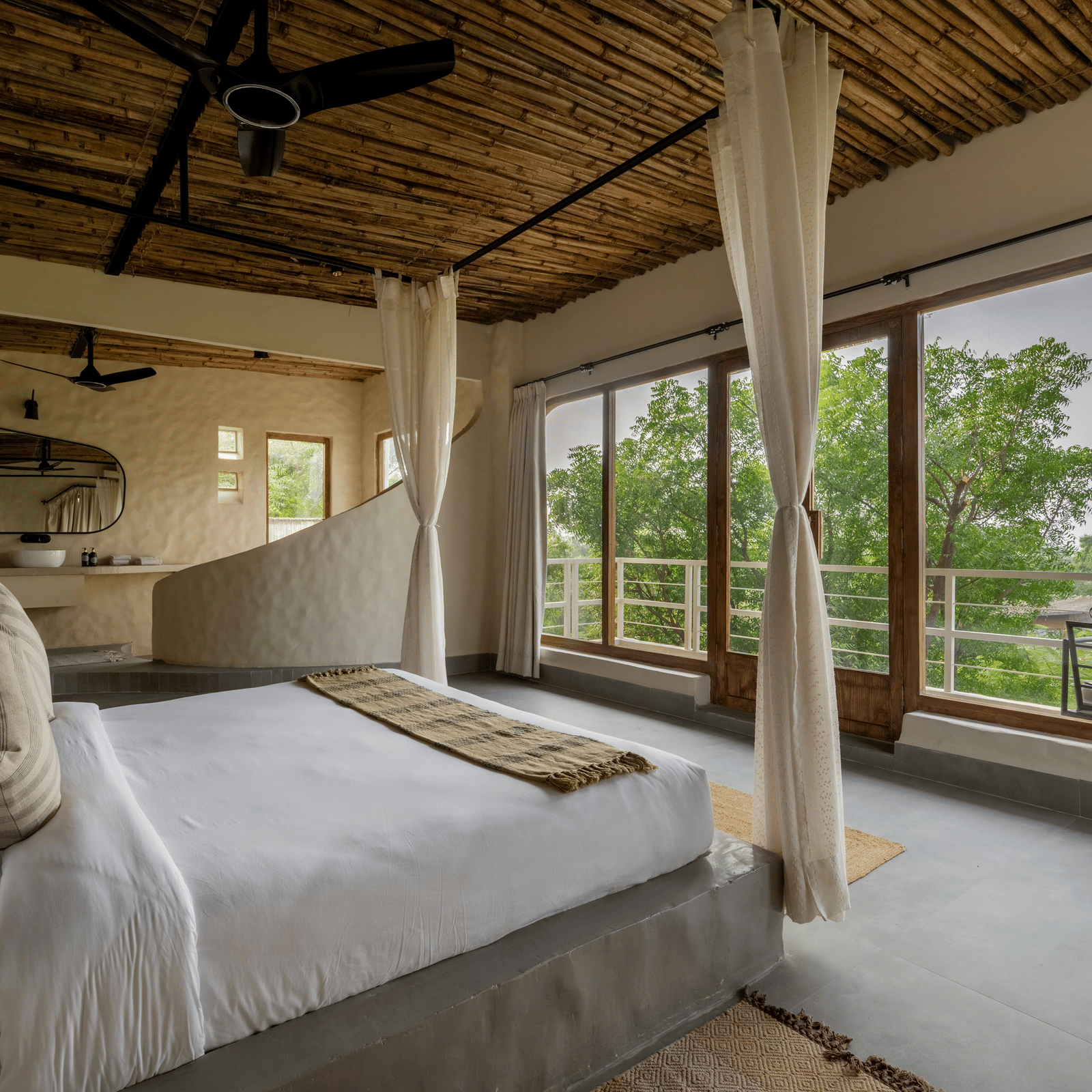 Bedroom with canopy bed, large windows, wooden ceiling, and serene outdoor views.