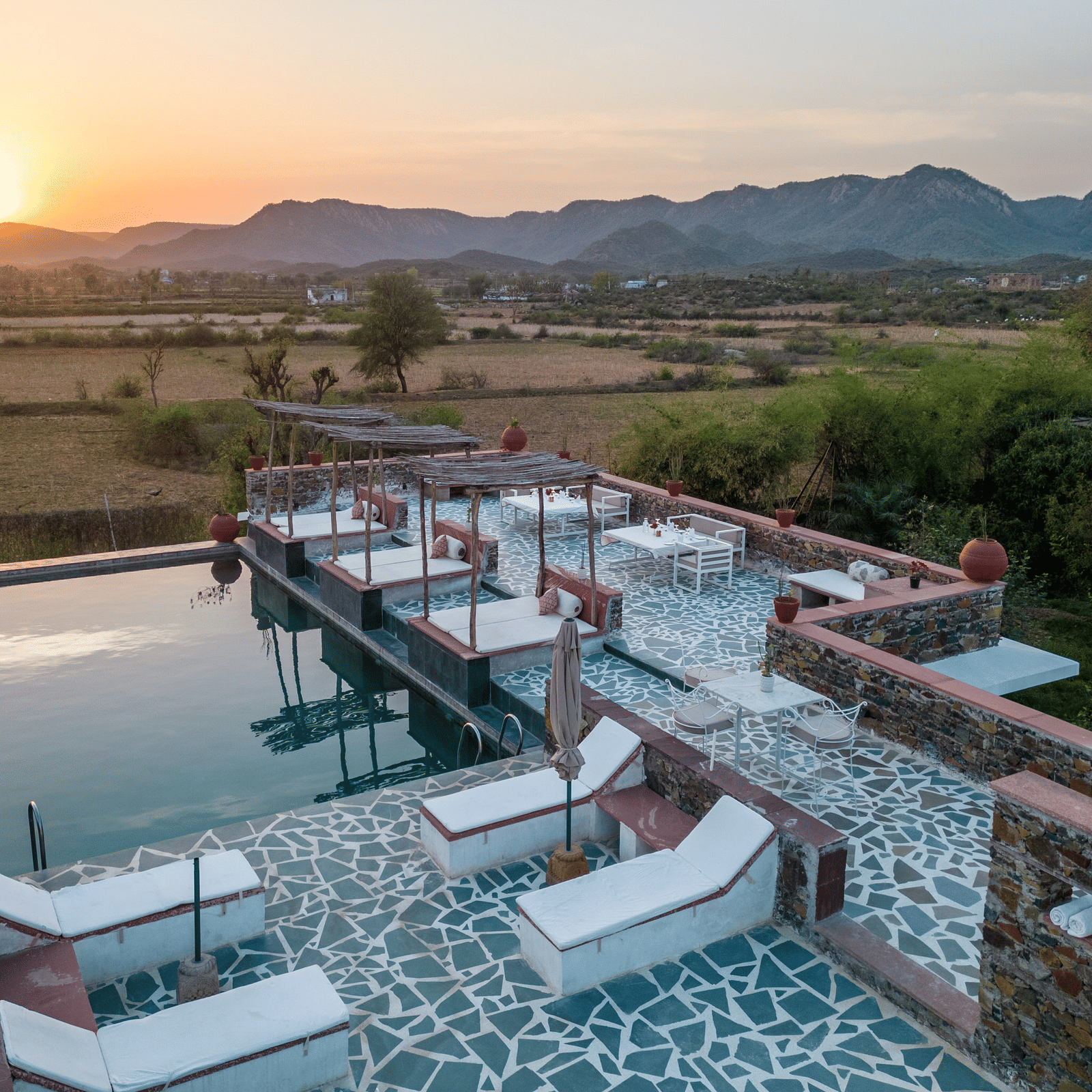 An aerial view image of a seating arrangement near the swimming pool in the open - Utsav Camp Sariska