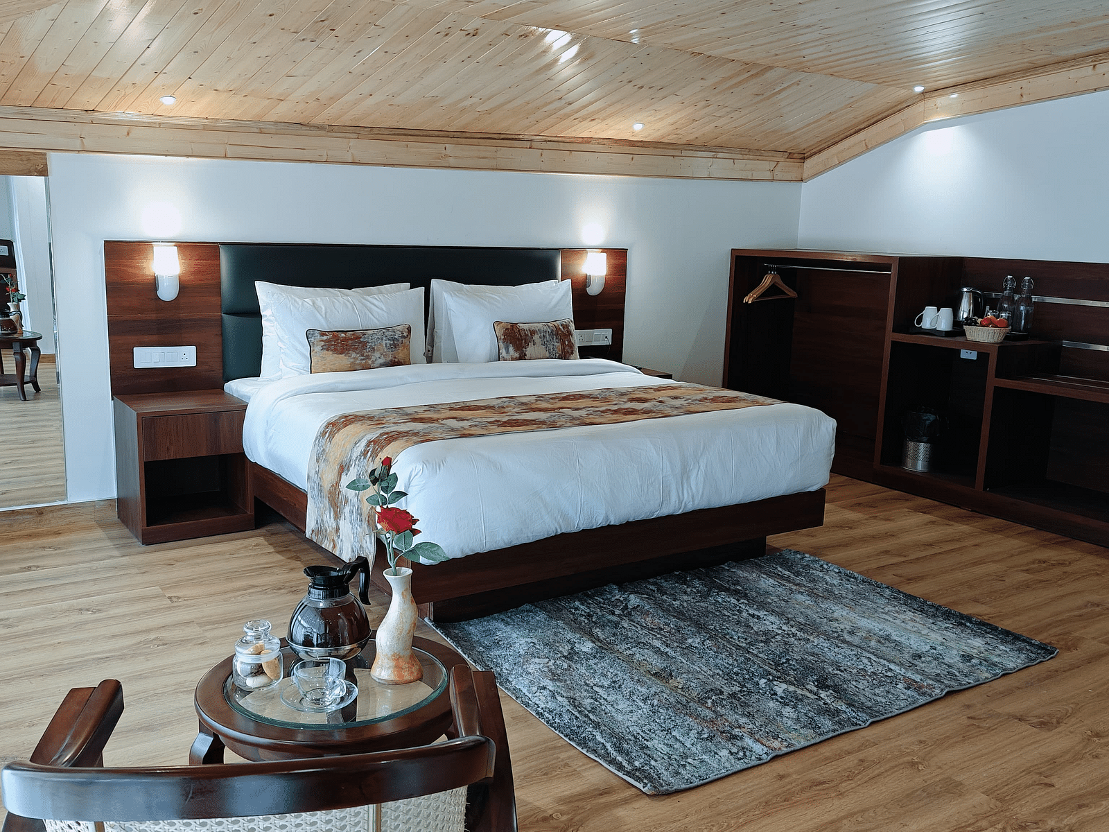 A hotel room in Darjeeling with a neatly made bed, side tables, and a patterned rug, offering a cosy and inviting feel - Sumitel JB Park, Darjeeling