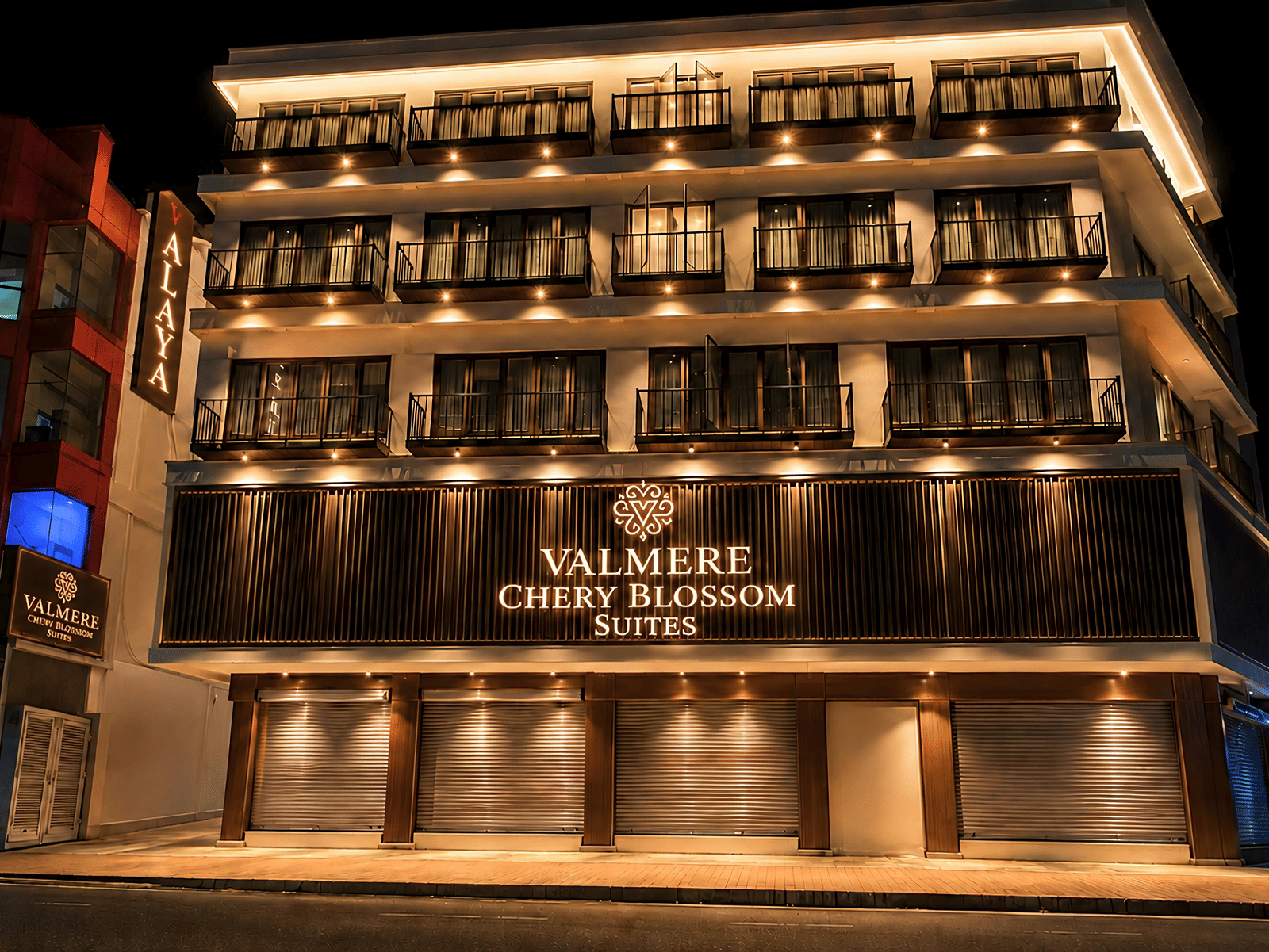 A 4-storey building of Valmere Chery Blossom Suites, illuminated at night with a sign board reflecting the signage of the hotel.
