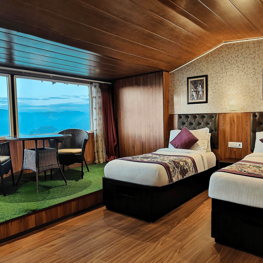 Twin bed room with large glass windows overlooking scenic hills at Mount Thistle Boutique Hotel, Darjeeling.