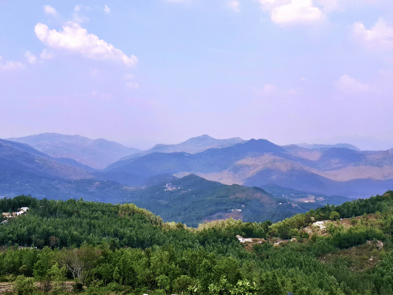 A distant view of layered mountain ridges under a partly cloudy sky.
