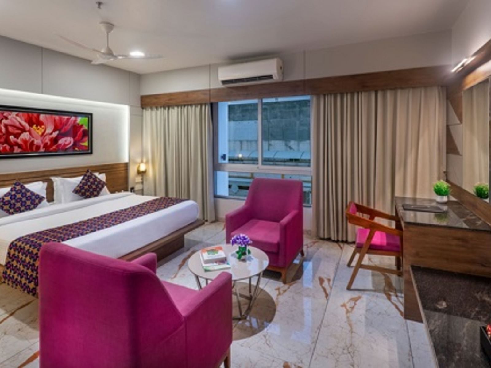 A room featuring a bed, a seating area with armchairs, and a television at Angel Lords Eco Inn Amreli.