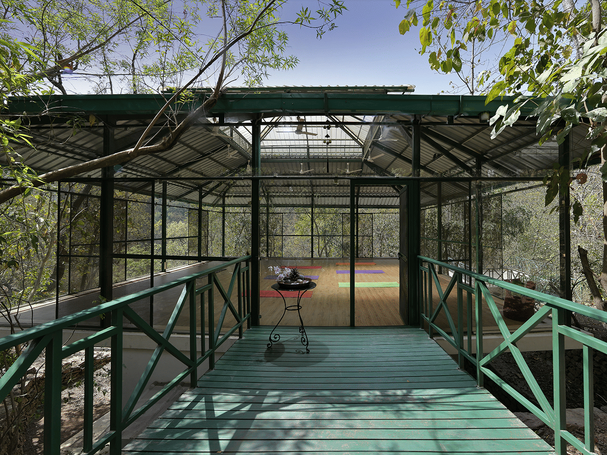 A green-coloured footbridge leading to a huge yoga hall at Neemrana's Glasshouse at The Ganges, Rishikesh.