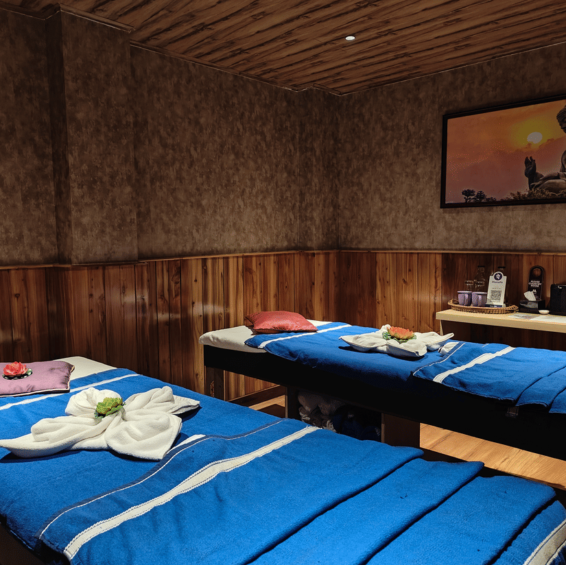 A spa room with twin massage beds, warm wooden interiors, soft lighting, and neatly arranged towels creating a calming wellness experience | Mount Lungta Boutique Hotel & Spa