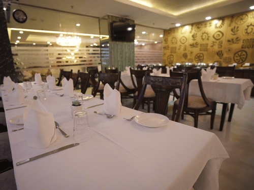 A close-up shot of cutlery arranged on the table with white sheet on at Dawat-e-Zaika - Hotel Atulyaa Taj, Agra
