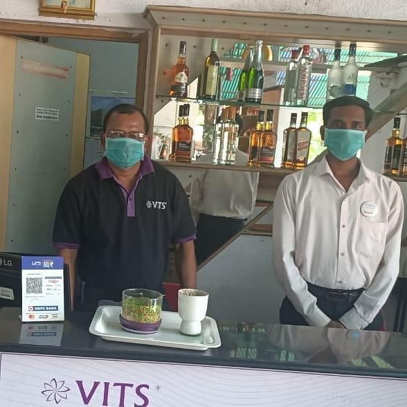 people behind a counter with vits hotels logo on the counter - VITS Hotels & Resorts