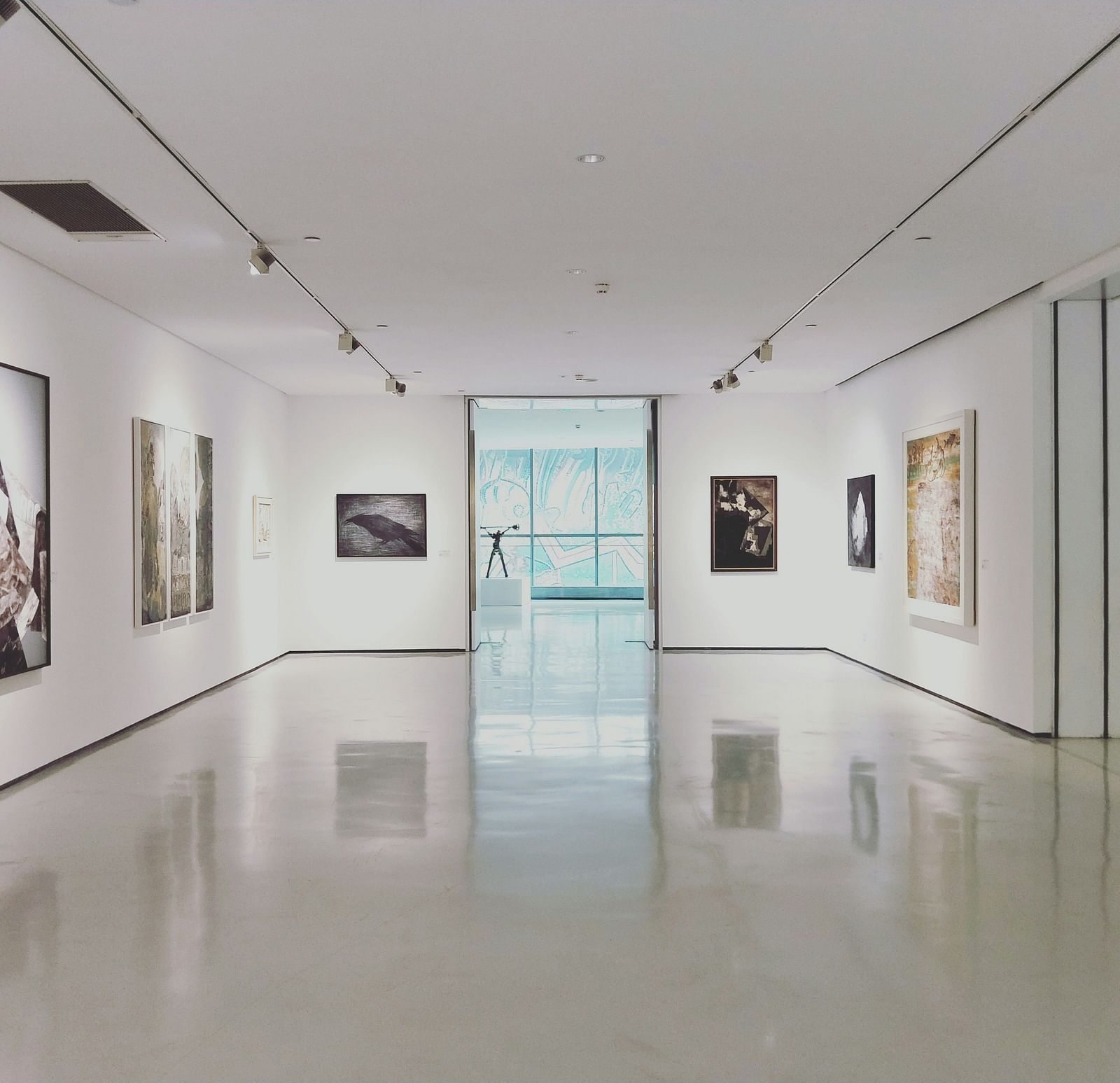 an overview of a museum with paintings hung on the wall and spotlight kept on it